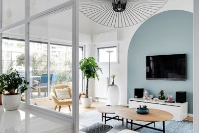 Exemple d'un grand salon moderne ouvert avec un mur bleu, un sol en bois brun, aucune cheminée, un téléviseur fixé au mur, un sol marron et un plafond cathédrale.