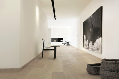 Geräumiges, Repräsentatives, Offenes Modernes Wohnzimmer mit weißer Wandfarbe, hellem Holzboden, Kaminofen, Kaminumrandung aus Stein, TV-Wand und braunem Boden in Nürnberg