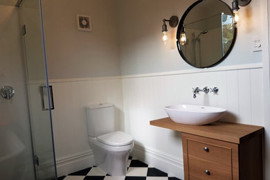 Inspiration for a mid-sized traditional master bathroom in Christchurch with furniture-like cabinets, medium wood cabinets, a claw-foot tub, a corner shower, a two-piece toilet, multi-coloured walls, vinyl floors, a vessel sink, wood benchtops, multi-coloured floor and a hinged shower door.