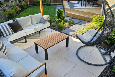 This is an example of a modern backyard concrete paver landscaping in Seattle with a pergola.