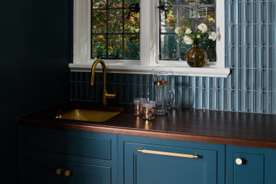 Wet bar - small traditional u-shaped light wood floor and brown floor wet bar idea in New York with an undermount sink, shaker cabinets, blue cabinets, wood countertops, blue backsplash, glass tile backsplash and brown countertops