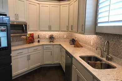 Photo of a mid-sized traditional u-shaped separate kitchen in Other with an undermount sink, shaker cabinets, white cabinets, granite benchtops, multi-coloured splashback, mosaic tile splashback, stainless steel appliances, dark hardwood floors, no island and brown floor.
