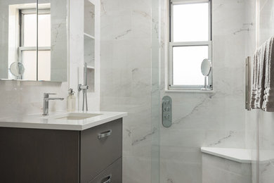 Inspiration for a mid-sized modern 3/4 bathroom in New York with flat-panel cabinets, grey cabinets, an alcove shower, gray tile, white tile, stone tile, multi-coloured walls, porcelain floors, an undermount sink, engineered quartz benchtops, brown floor, a sliding shower screen and white benchtops.