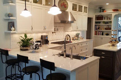 Inspiration for a mid-sized transitional u-shaped medium tone wood floor and brown floor open concept kitchen remodel in Atlanta with a farmhouse sink, shaker cabinets, white cabinets, quartz countertops, white backsplash, ceramic backsplash, stainless steel appliances and an island