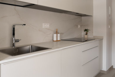 Photo of a large modern single-wall enclosed kitchen in Other with a submerged sink, flat-panel cabinets, all types of cabinet finish, engineered stone countertops, grey splashback, porcelain flooring, multiple islands, beige floors and white worktops.