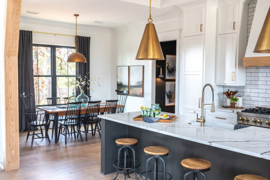 Large farmhouse l-shaped light wood floor and tray ceiling eat-in kitchen photo in Little Rock with a farmhouse sink, shaker cabinets, white cabinets, white backsplash, subway tile backsplash, stainless steel appliances, an island and white countertops