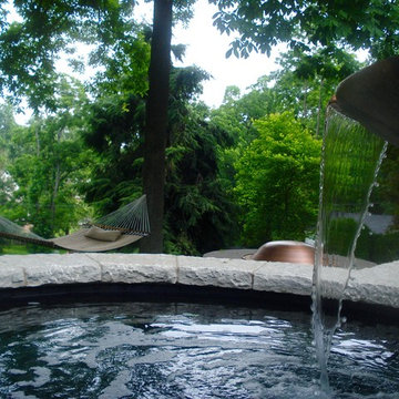 Cast stone bowl with scupper spills into water basin below.