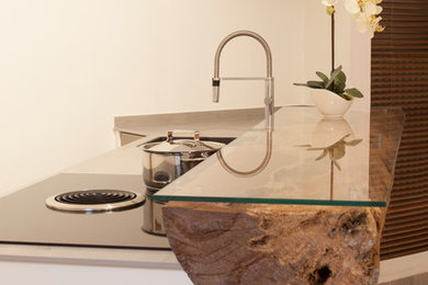 Offene, Einzeilige, Mittelgroße Moderne Küche mit Einbauwaschbecken, flächenbündigen Schrankfronten, weißen Schränken, Glas-Arbeitsplatte, Küchenrückwand in Weiß, dunklem Holzboden, Kücheninsel, braunem Boden und brauner Arbeitsplatte in München