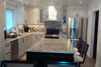 Inspiration for a mid-sized l-shaped porcelain tile eat-in kitchen remodel in Toronto with an undermount sink, raised-panel cabinets, white cabinets, granite countertops, multicolored backsplash, glass sheet backsplash, stainless steel appliances and an island