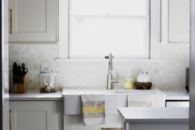 Example of a small transitional eat-in kitchen design in Columbus with a farmhouse sink, shaker cabinets, white cabinets, quartz countertops, gray backsplash, marble backsplash, stainless steel appliances and an island