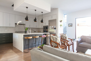 Inspiration for a mid-sized transitional u-shaped medium tone wood floor open concept kitchen remodel in Dallas with a double-bowl sink, shaker cabinets, white cabinets, quartz countertops, white backsplash, stone slab backsplash, stainless steel appliances and an island