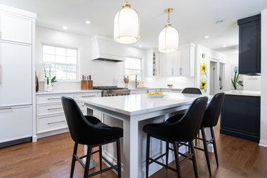 Mid-sized elegant l-shaped medium tone wood floor and brown floor eat-in kitchen photo in Other with an undermount sink, flat-panel cabinets, white cabinets, quartz countertops, paneled appliances, an island and white countertops