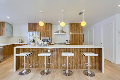 Inspiration for a large contemporary l-shaped laminate floor eat-in kitchen remodel in San Diego with flat-panel cabinets, brown cabinets, quartz countertops, white backsplash, porcelain backsplash, stainless steel appliances and an island