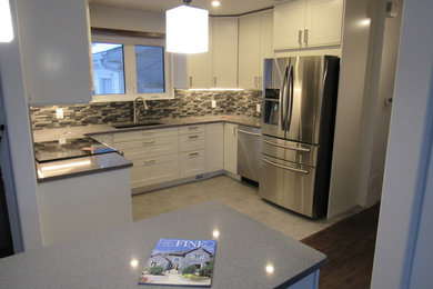 Foto de cocina de tamaño medio con armarios estilo shaker, puertas de armario blancas, encimera de cuarcita, salpicadero verde, una isla y encimeras grises
