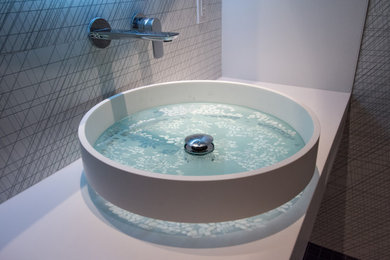 Small minimalist black and white tile and ceramic tile mosaic tile floor and black floor powder room photo in Charlotte with white cabinets, a bidet, black walls, a vessel sink, solid surface countertops, white countertops and a built-in vanity