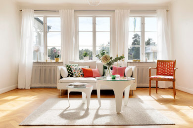 This is an example of a mid-sized scandinavian formal open concept living room in Stockholm with white walls, light hardwood floors and no tv.