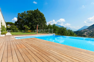 Foto di una grande piscina a sfioro infinito minimalista rettangolare davanti casa con pedane
