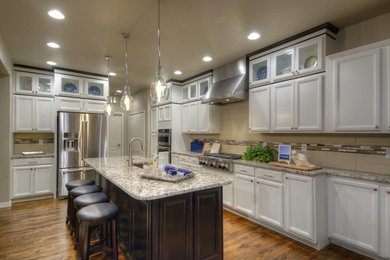 Open concept kitchen - mid-sized transitional single-wall dark wood floor open concept kitchen idea in Denver with an undermount sink, recessed-panel cabinets, white cabinets, granite countertops, gray backsplash, glass tile backsplash, stainless steel appliances and an island