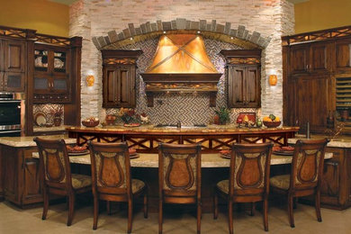 Example of a classic concrete floor and beige floor kitchen design in Denver with an undermount sink, raised-panel cabinets, dark wood cabinets, granite countertops, multicolored backsplash, mosaic tile backsplash, stainless steel appliances and an island