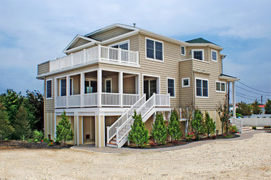 Example of a beach style beige three-story vinyl exterior home design in New York