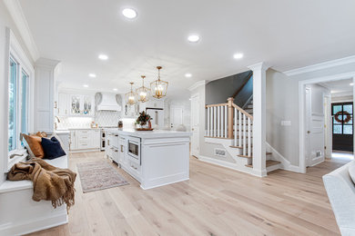 Inspiration for a large timeless l-shaped light wood floor and beige floor open concept kitchen remodel in Atlanta with an undermount sink, beaded inset cabinets, white cabinets, quartz countertops, white backsplash, marble backsplash, white appliances, an island and white countertops