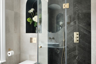 This is an example of a medium sized contemporary shower room bathroom in London with recessed-panel cabinets, black cabinets, a walk-in shower, a wall mounted toilet, black tiles, porcelain tiles, beige walls, limestone flooring, a console sink, quartz worktops, black floors, a hinged door, white worktops, a shower bench, a single sink and a freestanding vanity unit.