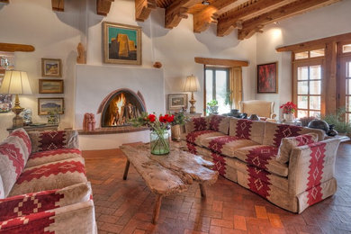 This is an example of a large enclosed living room in Albuquerque with white walls, brick floors, a standard fireplace, a plaster fireplace surround and no tv.