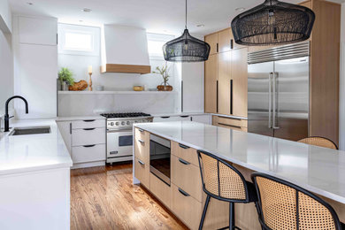 Large contemporary u-shaped kitchen/diner in Chicago with a submerged sink, flat-panel cabinets, light wood cabinets, engineered stone countertops, engineered quartz splashback, stainless steel appliances, an island and white worktops.