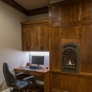 Inspiration för ett litet rustikt hemmabibliotek, med grå väggar, mörkt trägolv, en öppen vedspis, en spiselkrans i metall, ett inbyggt skrivbord och brunt golv