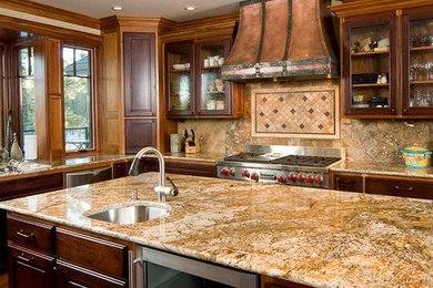 Example of a mid-sized arts and crafts l-shaped light wood floor enclosed kitchen design in Boston with an undermount sink, glass-front cabinets, medium tone wood cabinets, granite countertops, beige backsplash, stone slab backsplash, stainless steel appliances and an island
