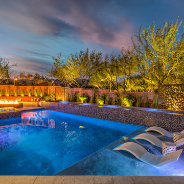Contemporary Backyard Pool with Tiled Water Feature, Rim Flow Spa, & Fire Pit