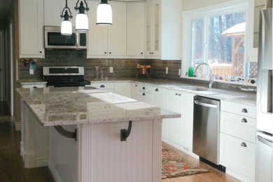 Inspiration for a large timeless l-shaped medium tone wood floor open concept kitchen remodel in Salt Lake City with an undermount sink, stainless steel appliances, shaker cabinets, white cabinets, marble countertops, brown backsplash, glass tile backsplash and an island