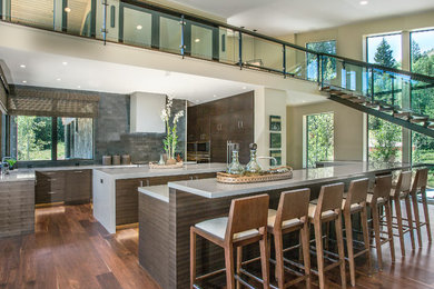 Inspiration for a large contemporary medium tone wood floor eat-in kitchen remodel in Salt Lake City with flat-panel cabinets, an undermount sink, dark wood cabinets, quartzite countertops, gray backsplash, stone tile backsplash, paneled appliances and two islands