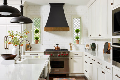 Inspiration for a large timeless l-shaped medium tone wood floor and brown floor open concept kitchen remodel in Minneapolis with a farmhouse sink, shaker cabinets, white cabinets, quartz countertops, white backsplash, ceramic backsplash, stainless steel appliances, an island and white countertops