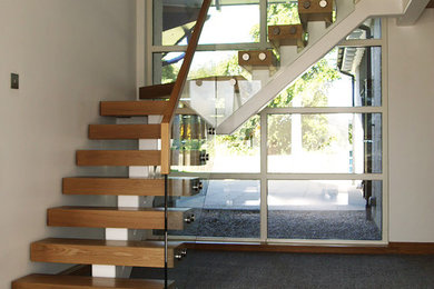 Inspiration for a mid-sized modern wood floating staircase in Other with open risers and glass railing.