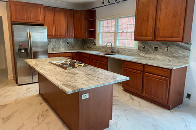 Porcelain tile and white floor eat-in kitchen photo in Baltimore with a double-bowl sink, medium tone wood cabinets, granite countertops, white backsplash, granite backsplash, stainless steel appliances, an island and white countertops