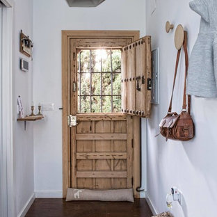 Foto på en eklektisk hall, med vita väggar, mörkt trägolv, en tvådelad stalldörr och ljus trädörr