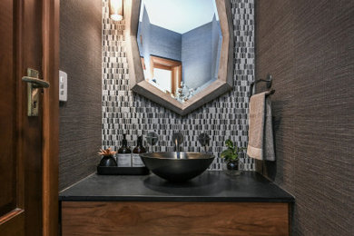 Photo of a small contemporary powder room in Sydney with flat-panel cabinets, medium wood cabinets, black and white tile, mosaic tile, terrazzo floors, a vessel sink, engineered quartz benchtops, black benchtops, a floating vanity and wallpaper.