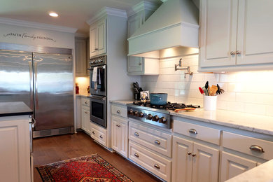 Mid-sized farmhouse l-shaped medium tone wood floor and brown floor eat-in kitchen photo in Other with an undermount sink, raised-panel cabinets, white cabinets, white backsplash, subway tile backsplash, stainless steel appliances and an island