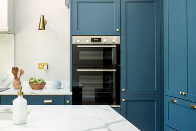 Photo of a contemporary l-shaped kitchen/diner in Other with shaker cabinets, blue cabinets, quartz worktops, white splashback, stone slab splashback, black appliances, an island, white worktops and a vaulted ceiling.