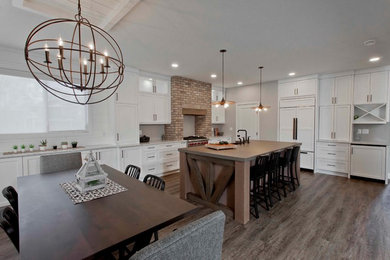 Inspiration for a large country u-shaped eat-in kitchen in Calgary with a farmhouse sink, recessed-panel cabinets, white cabinets, quartz benchtops, panelled appliances, dark hardwood floors, with island, brown floor and grey benchtop.
