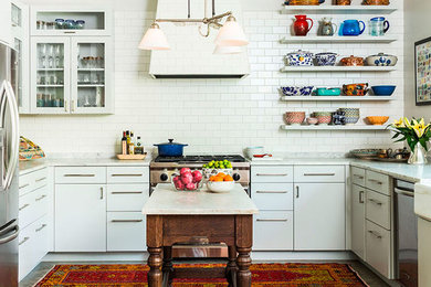 Example of a mid-sized trendy l-shaped concrete floor and gray floor open concept kitchen design in Austin with a farmhouse sink, flat-panel cabinets, white cabinets, marble countertops, white backsplash, subway tile backsplash, stainless steel appliances and an island