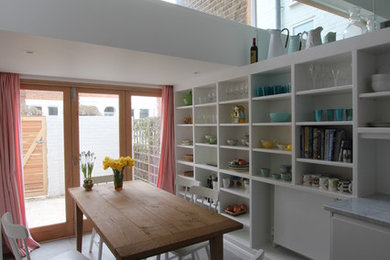 Contemporary kitchen/dining combo in London with white walls and porcelain floors.