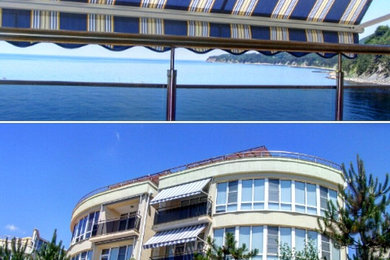 На фото: балкон и лоджия среднего размера в современном стиле с навесом и стеклянными перилами с