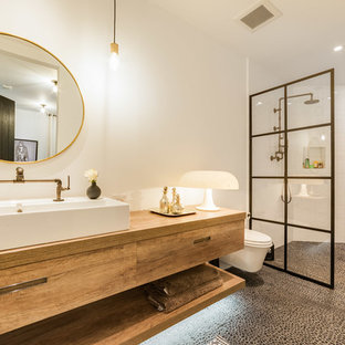 Example of a large trendy 3/4 white tile pebble tile floor and gray floor bathroom design in Los Angeles with white walls, wood countertops, flat-panel cabinets, light wood cabinets, a wall-mount toilet and a vessel sink