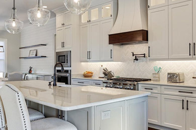 Inspiration for a large traditional eat-in kitchen in New Orleans with a farmhouse sink, white cabinets, marble benchtops, white splashback, stainless steel appliances, dark hardwood floors, with island, brown floor and white benchtop.