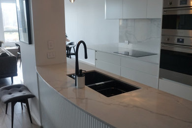 Exempel på ett mellanstort modernt vit vitt kök, med en undermonterad diskho, släta luckor, vita skåp, bänkskiva i kvarts, vitt stänkskydd, rostfria vitvaror, mellanmörkt trägolv och en köksö