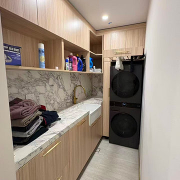 Utility Laundry Room – Oak Cabinetry, Marble Counter & Stacked Washer Dryer Unit