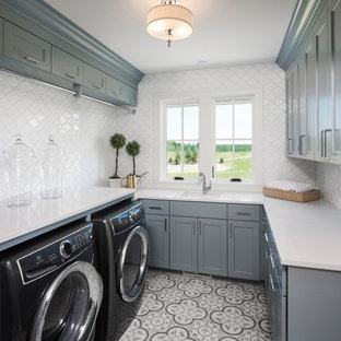 Idee per una sala lavanderia tradizionale con ante in stile shaker, ante grigie, top in vetro, paraspruzzi bianco, lavatrice e asciugatrice affiancate, pavimento multicolore e top bianco