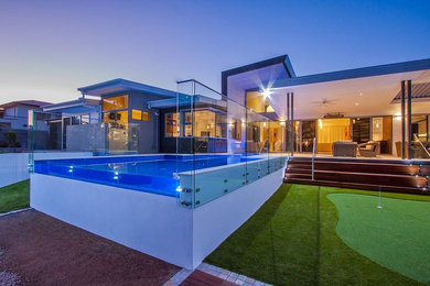 Photo of a large contemporary courtyard rectangular aboveground pool in Brisbane with a water feature and natural stone pavers.